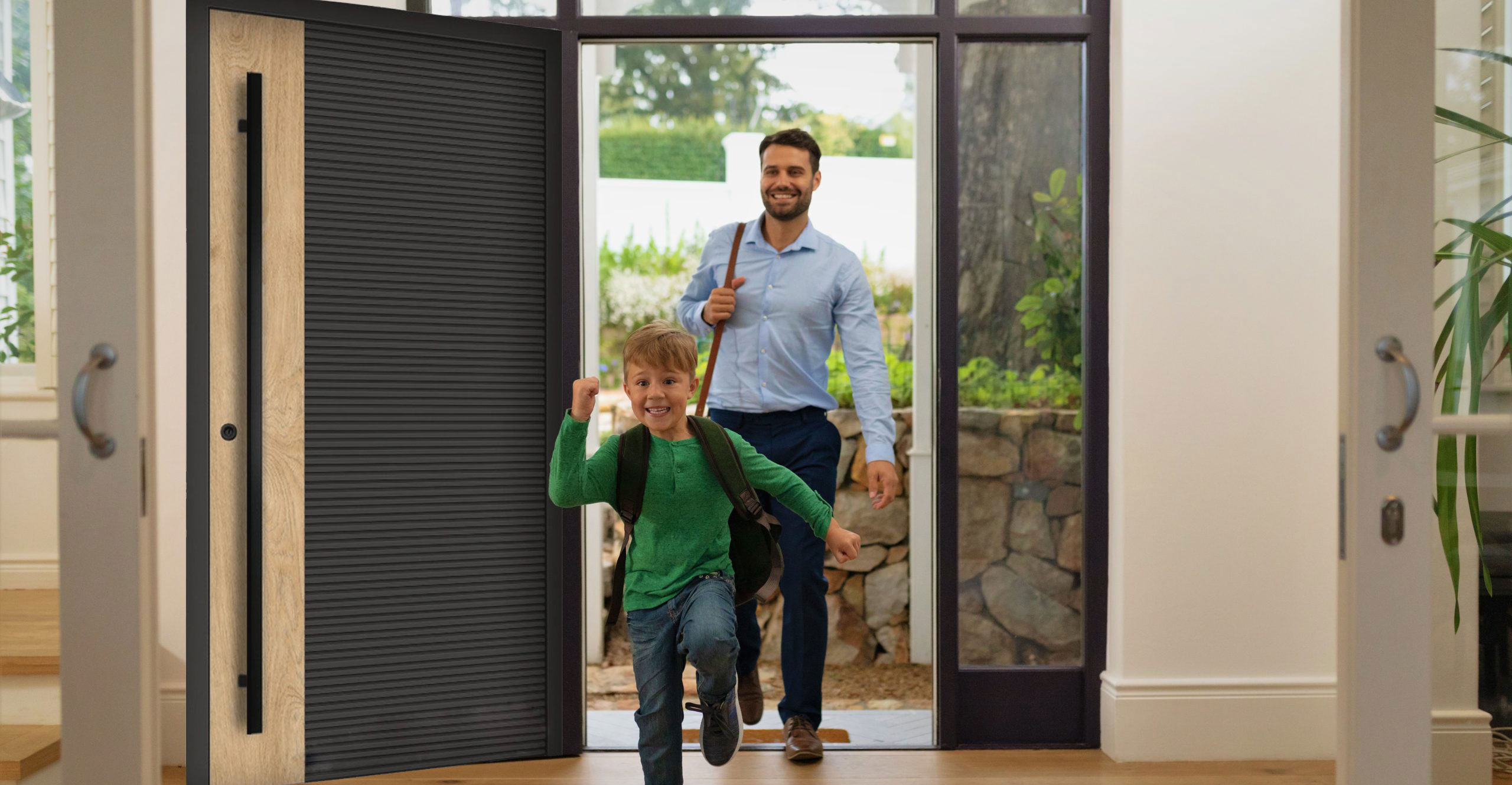 Ilustracja przedstawia tatę i syna, którzy wchodzą do domu przez drzwi wejściowe w kolorze okleiny Woodec Malt.